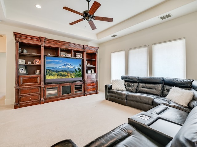 living room with a tray ceiling, carpet floors, and ceiling fan