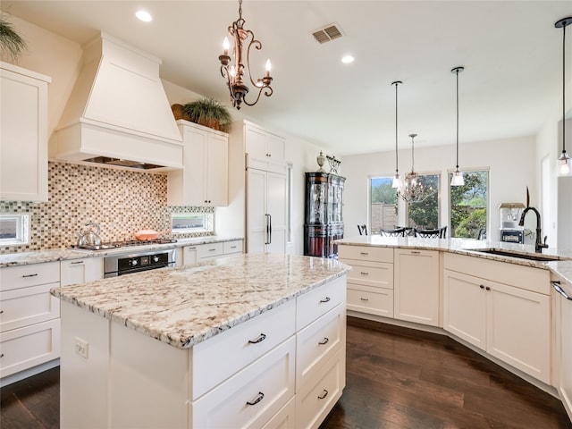 kitchen featuring custom range hood, dark hardwood / wood-style flooring, a center island, and hanging light fixtures