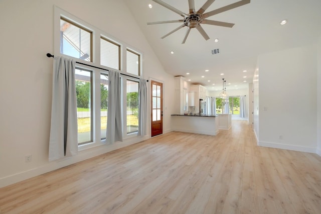 unfurnished living room featuring ceiling fan, high vaulted ceiling, light wood-type flooring, and plenty of natural light