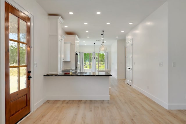 kitchen with white cabinetry, light hardwood / wood-style floors, kitchen peninsula, and pendant lighting