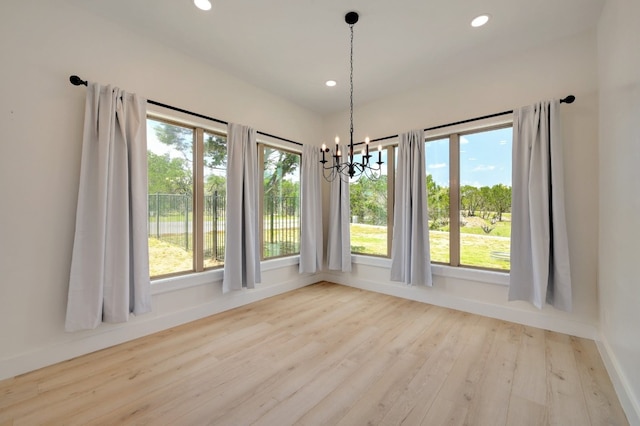 unfurnished dining area with light hardwood / wood-style floors, a healthy amount of sunlight, and a chandelier