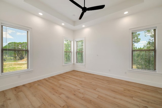 spare room featuring a healthy amount of sunlight, light hardwood / wood-style floors, and ceiling fan