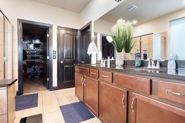 full bathroom featuring double vanity, visible vents, tile patterned floors, a shower stall, and a sink