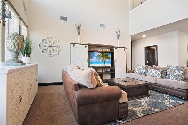 carpeted living room featuring a towering ceiling and a barn door