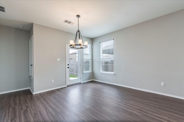 empty room with dark wood-type flooring and a chandelier