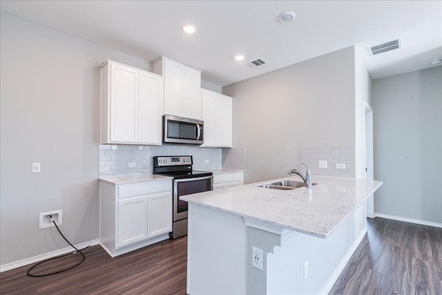 kitchen featuring appliances with stainless steel finishes, sink, dark hardwood / wood-style flooring, kitchen peninsula, and white cabinets