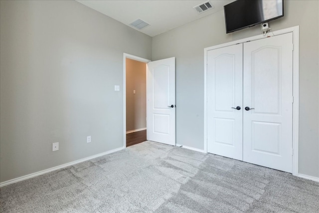 unfurnished bedroom featuring a closet and light colored carpet