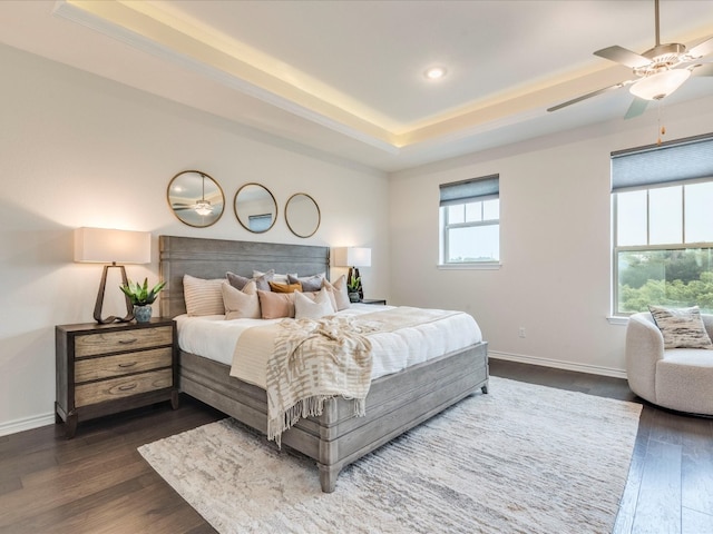 bedroom featuring a raised ceiling, ceiling fan, and dark hardwood / wood-style flooring