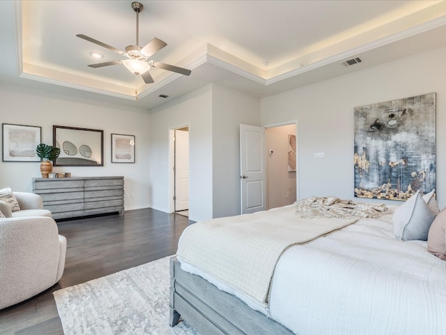 bedroom with a raised ceiling, ceiling fan, and dark hardwood / wood-style floors