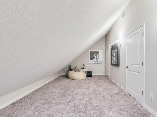 bonus room with a textured ceiling, light colored carpet, and lofted ceiling