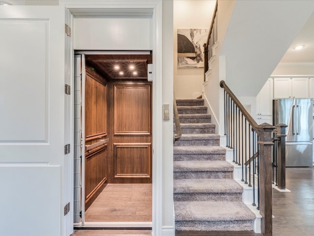 stairway with hardwood / wood-style floors, elevator, and crown molding