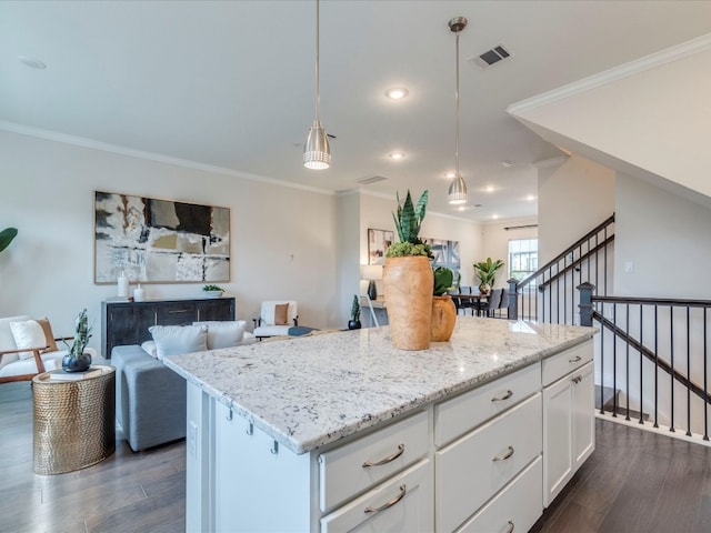 kitchen featuring dark wood-type flooring, a kitchen island, pendant lighting, white cabinets, and ornamental molding