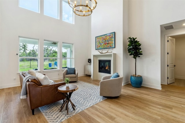 living room with a high ceiling, a notable chandelier, and light wood-type flooring