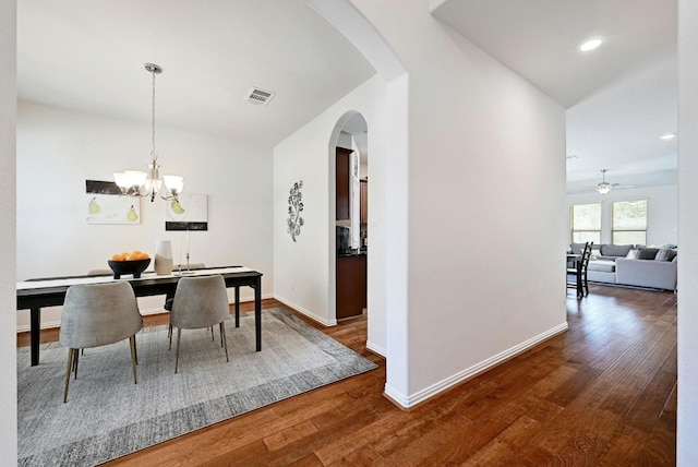 dining space with ceiling fan with notable chandelier and hardwood / wood-style flooring