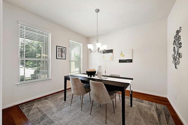 dining area with dark wood-type flooring and a chandelier