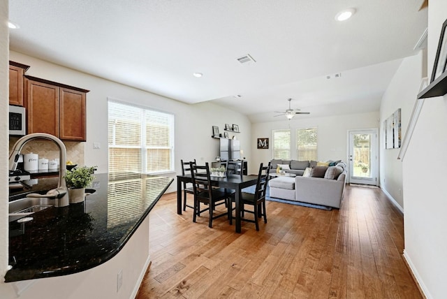 dining room featuring ceiling fan, sink, lofted ceiling, and light wood-type flooring