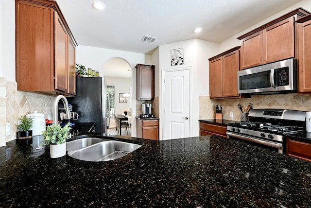 kitchen with backsplash, dark stone countertops, and appliances with stainless steel finishes