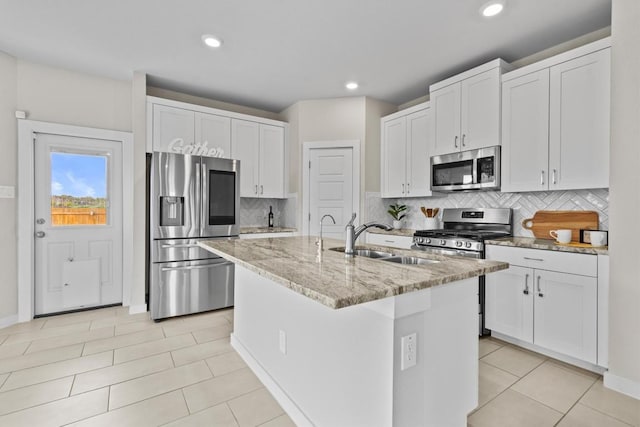 kitchen with a center island with sink, white cabinets, sink, and appliances with stainless steel finishes