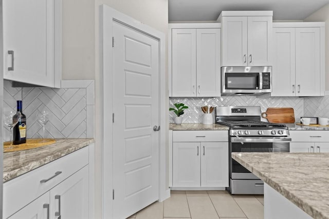 kitchen featuring backsplash, white cabinetry, stainless steel appliances, and light tile patterned floors