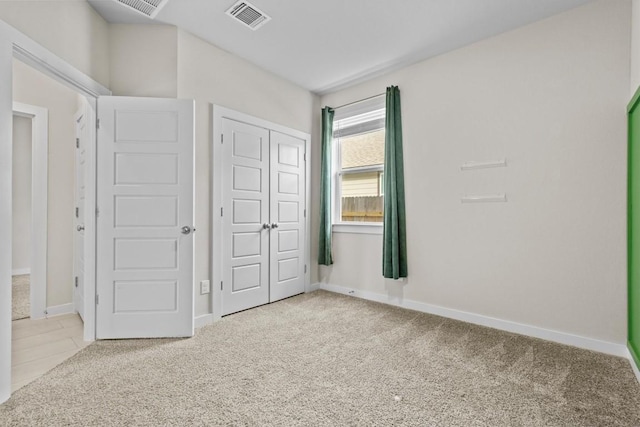 unfurnished bedroom with light colored carpet and a closet