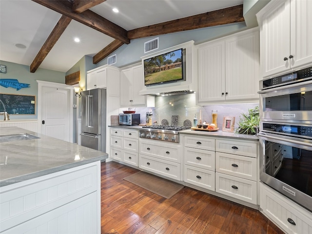 kitchen featuring dark hardwood / wood-style floors, stainless steel appliances, backsplash, lofted ceiling with beams, and white cabinetry