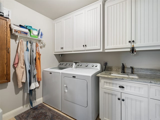 laundry area with sink, washing machine and clothes dryer, and cabinets