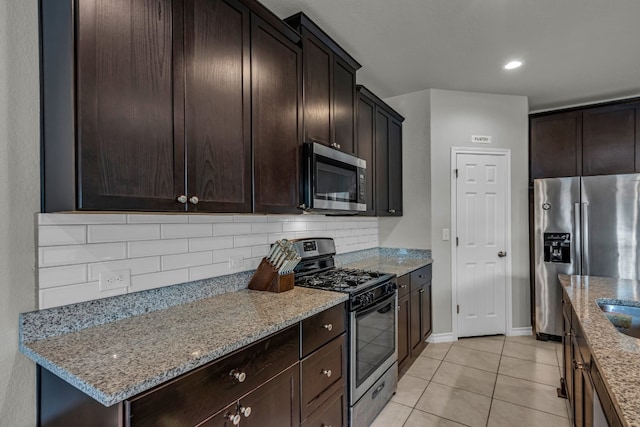 kitchen with light stone countertops, dark brown cabinetry, appliances with stainless steel finishes, and light tile patterned flooring