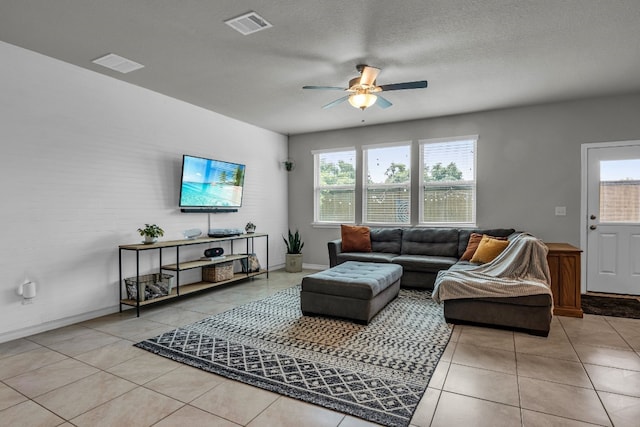 tiled living room featuring a textured ceiling, ceiling fan, and plenty of natural light