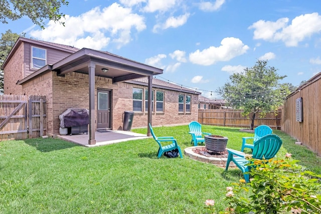 rear view of property with a yard, a patio area, and a fire pit