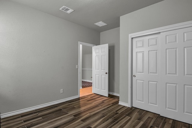 unfurnished bedroom featuring dark wood-type flooring and a closet