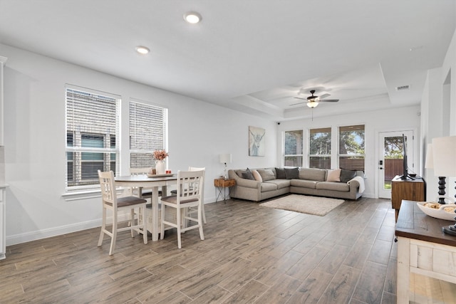 living room featuring a raised ceiling, hardwood / wood-style flooring, and ceiling fan