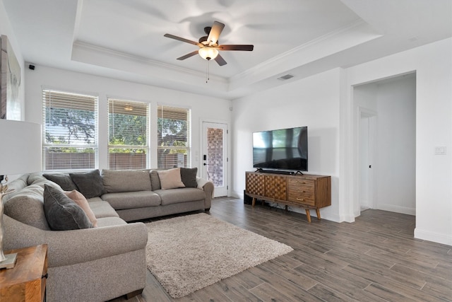 living room with dark hardwood / wood-style flooring, crown molding, ceiling fan, and a raised ceiling