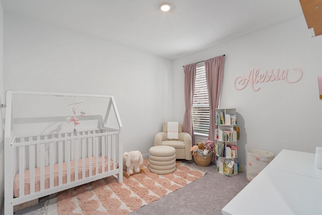 bedroom featuring a nursery area and carpet