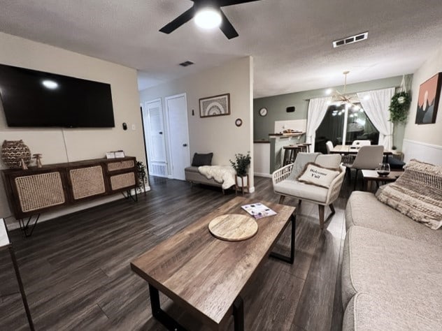 living room with ceiling fan, a textured ceiling, and dark hardwood / wood-style flooring