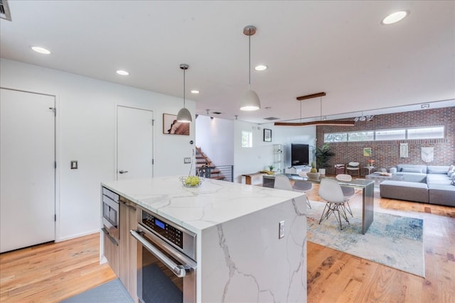 kitchen featuring brick wall, built in microwave, pendant lighting, a center island, and oven