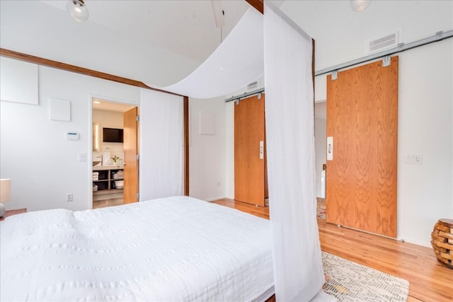 bedroom with hardwood / wood-style floors and a barn door