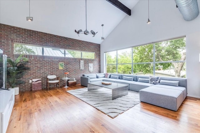 living room with a high ceiling, light wood-type flooring, plenty of natural light, and brick wall