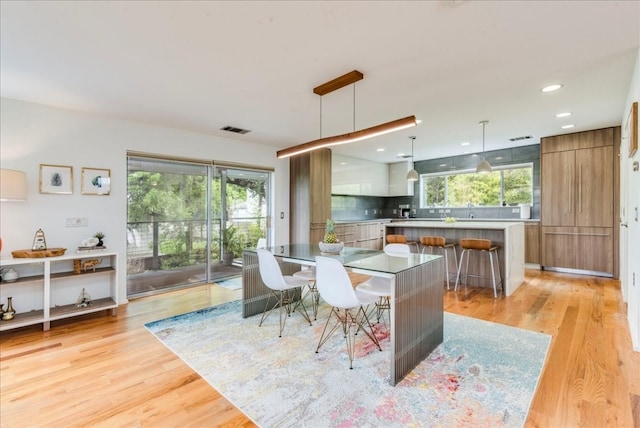 kitchen with a center island, backsplash, hanging light fixtures, light hardwood / wood-style floors, and a breakfast bar area