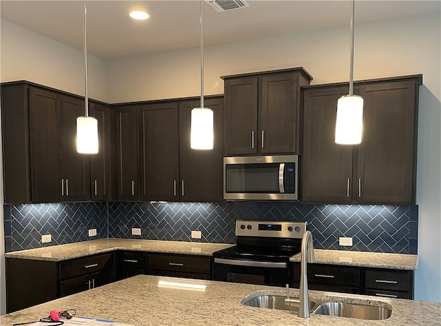 kitchen featuring dark brown cabinetry, appliances with stainless steel finishes, and decorative light fixtures