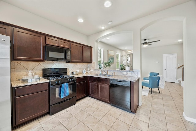 kitchen with arched walkways, black appliances, backsplash, and light stone countertops