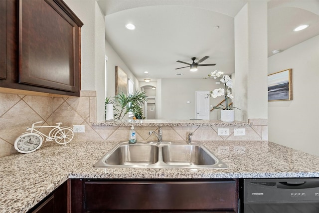 kitchen featuring black dishwasher, tasteful backsplash, a sink, dark brown cabinetry, and light stone countertops