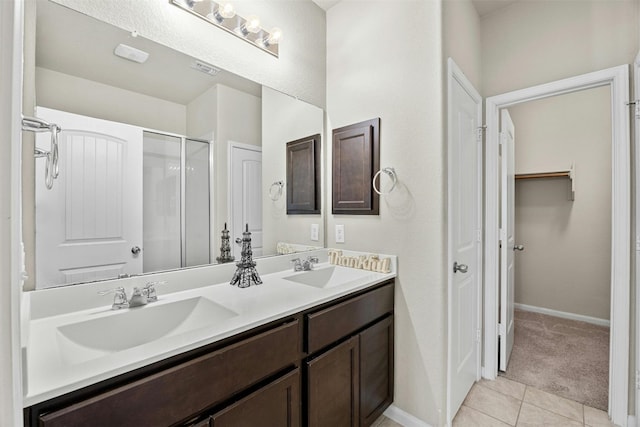 bathroom with a walk in closet, tile patterned flooring, a sink, and double vanity