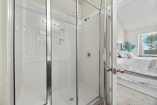 bathroom featuring a shower with door and vaulted ceiling