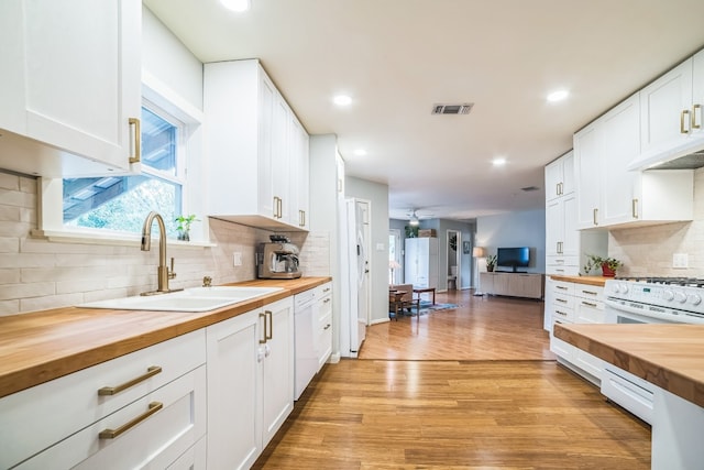 kitchen with wood counters, sink, decorative backsplash, and white cabinets