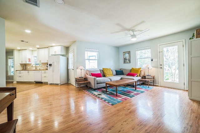 living room featuring plenty of natural light, sink, ceiling fan, and light hardwood / wood-style flooring