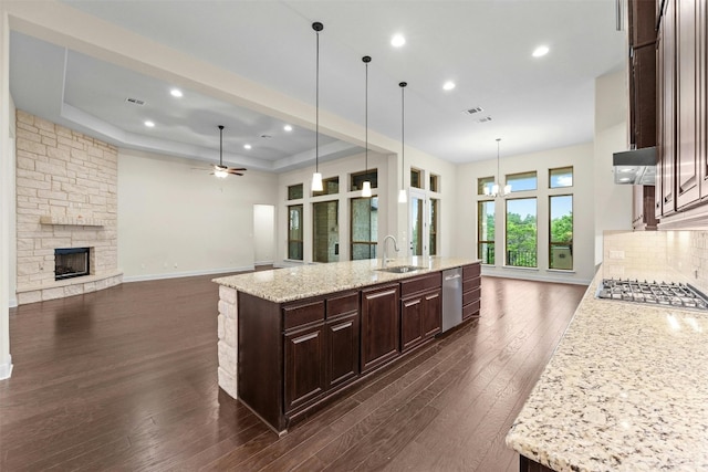 kitchen with a large island with sink, sink, pendant lighting, appliances with stainless steel finishes, and dark hardwood / wood-style flooring