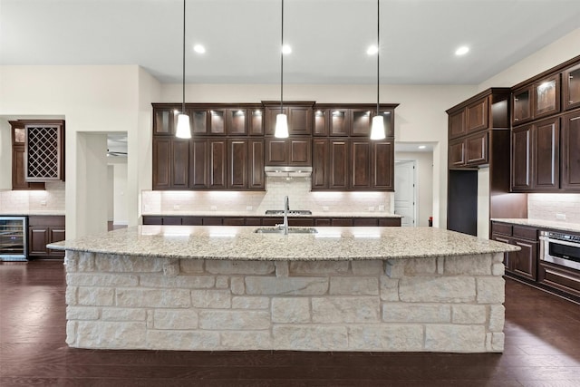 kitchen featuring decorative backsplash, dark wood-type flooring, and a center island with sink