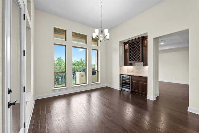 interior space with wine cooler, dark hardwood / wood-style flooring, bar area, and a chandelier