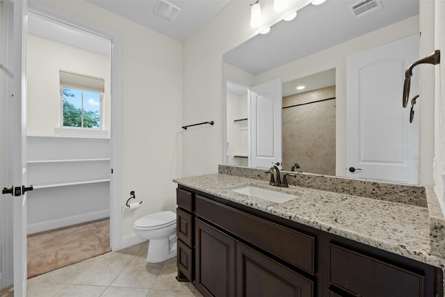 bathroom with toilet, vanity, and tile patterned flooring