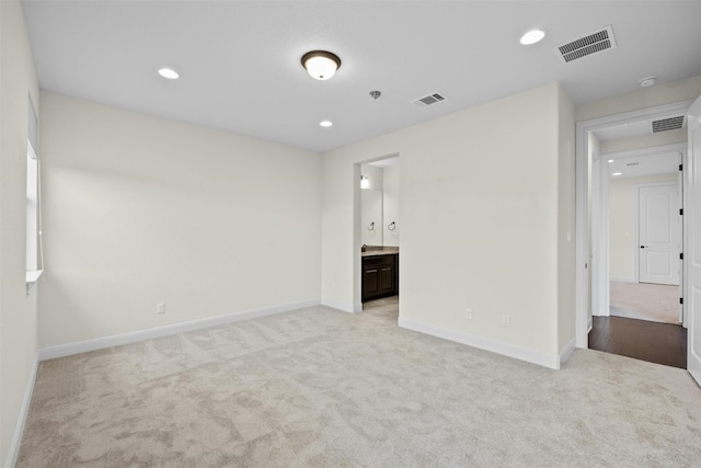 unfurnished bedroom featuring light colored carpet and ensuite bath